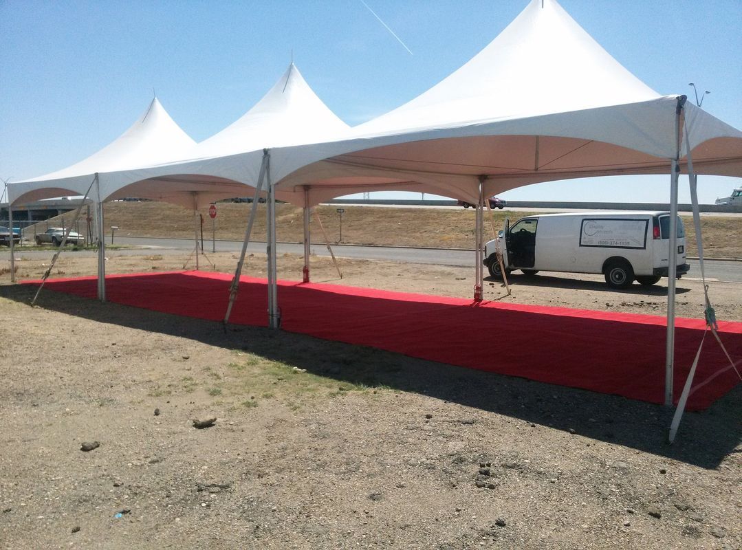 A white van is parked under a white tent