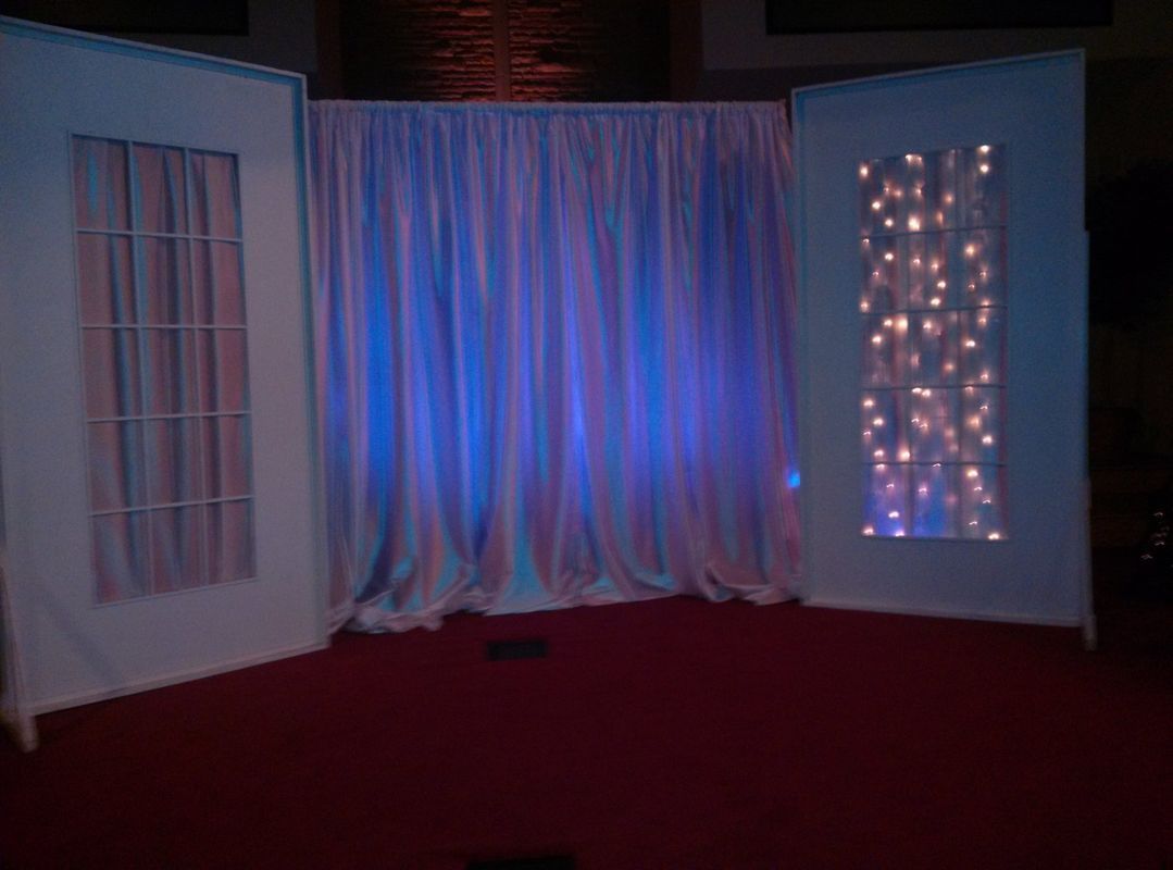 A stage with a white curtain and blue lights on it
