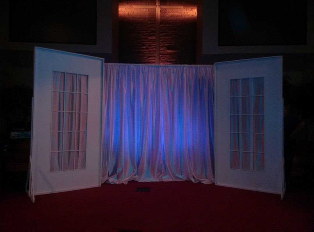 A stage with a blue light behind it and a cross in the background