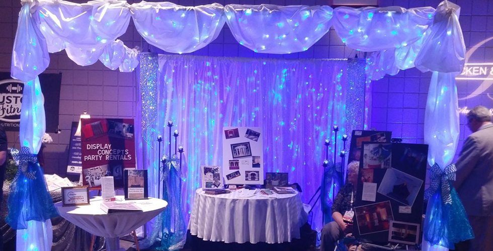 A table with a white tablecloth is sitting under a canopy with blue lights