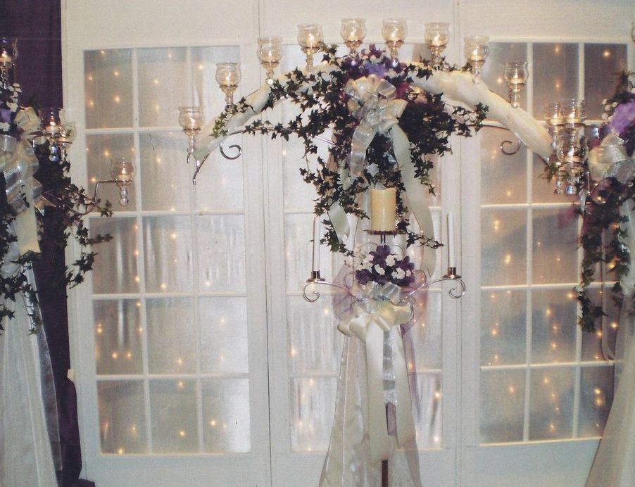 A wedding arch decorated with candles and flowers