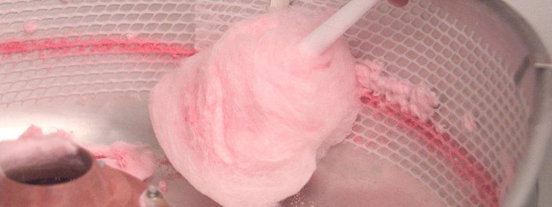 A close up of a person holding a pink lollipop