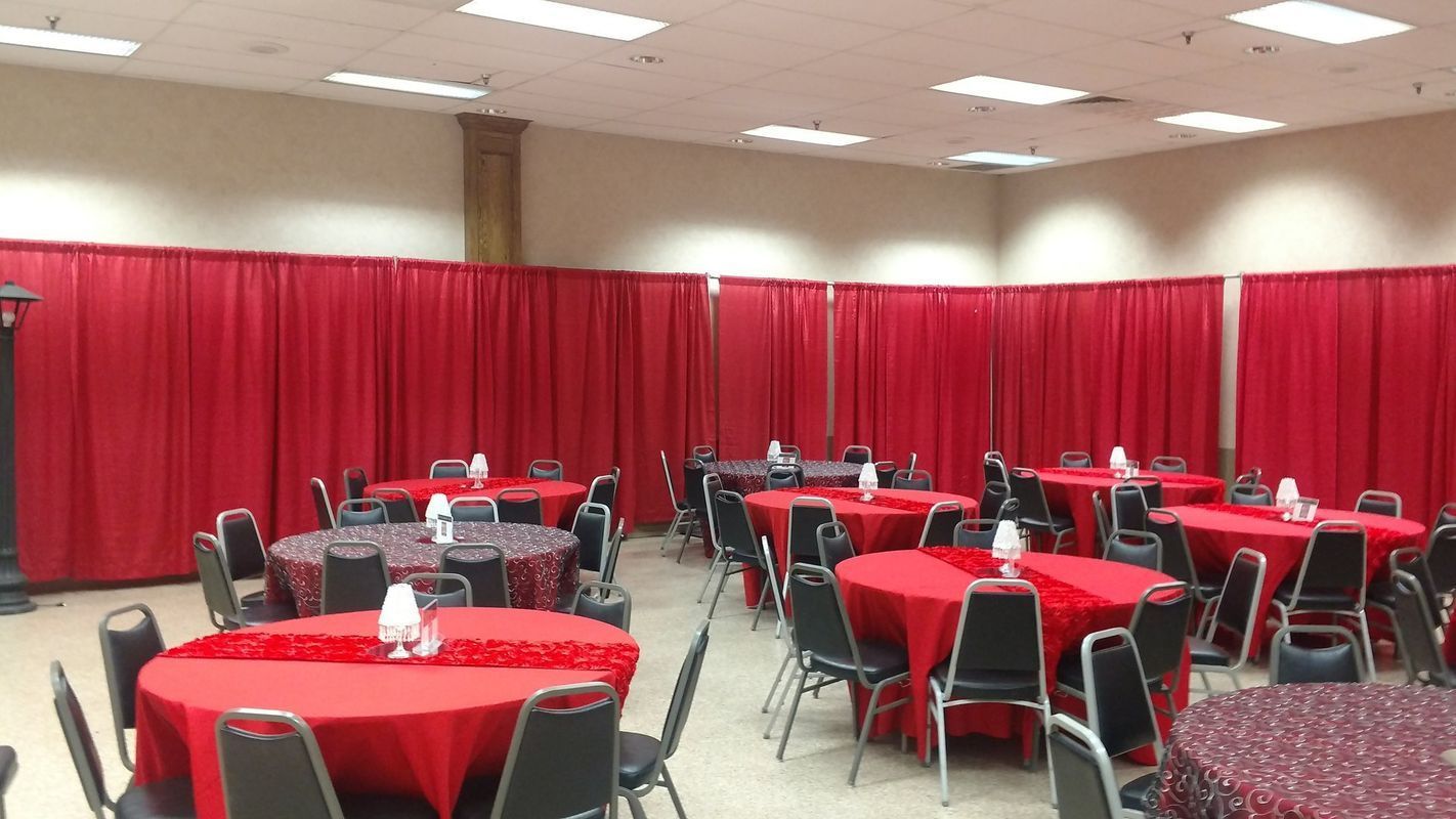 A large room with tables and chairs and red curtains