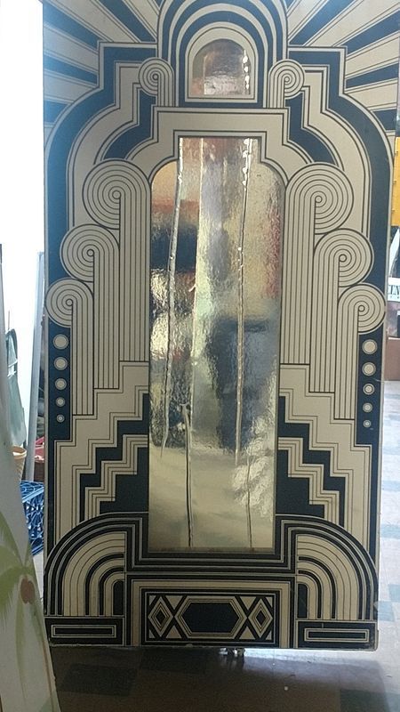 A black and white art deco mirror is sitting on a wooden floor