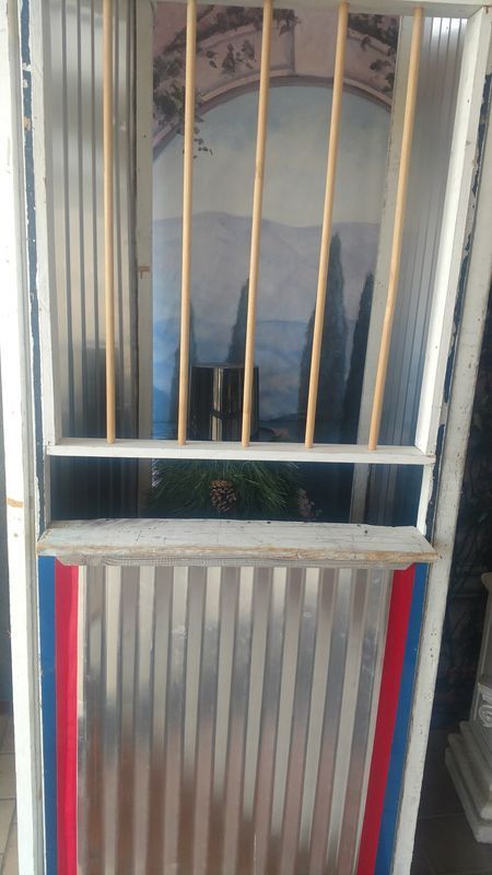 A metal door with a painting on the wall behind it