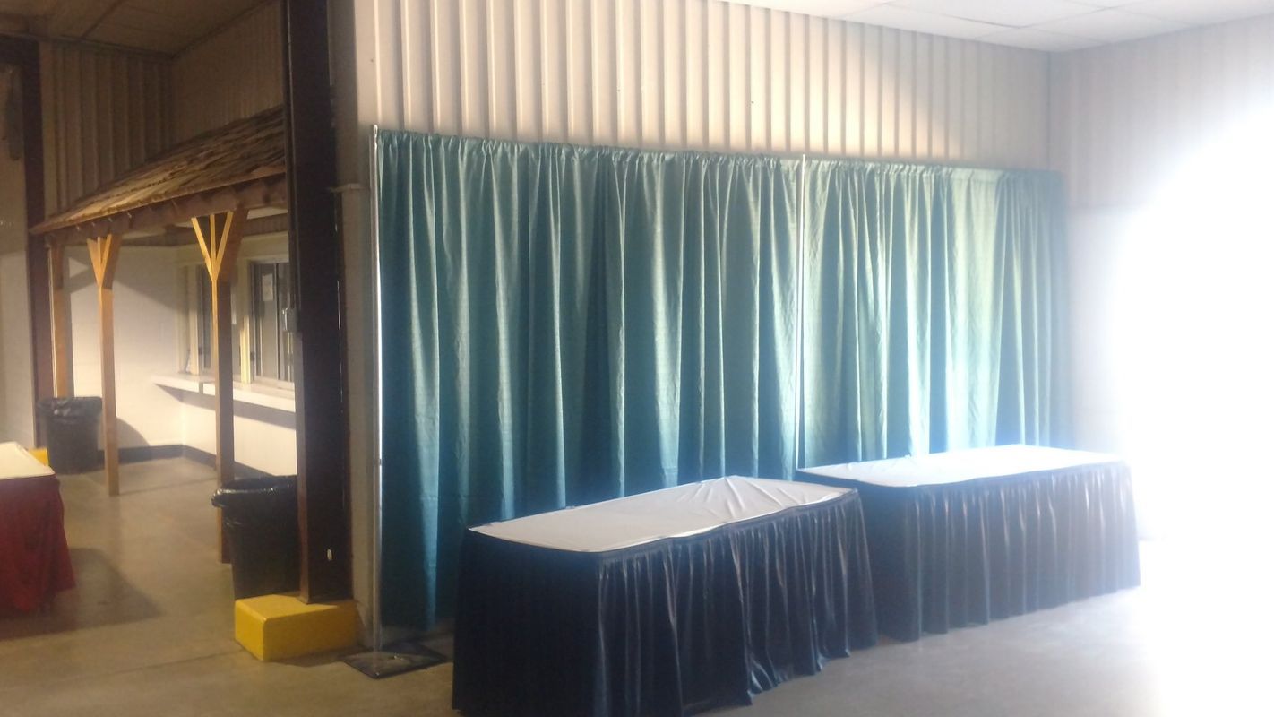There are two tables in the room with blue curtains behind them