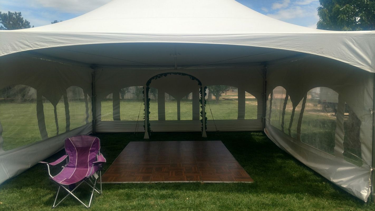 A white tent with a wooden dance floor inside of it