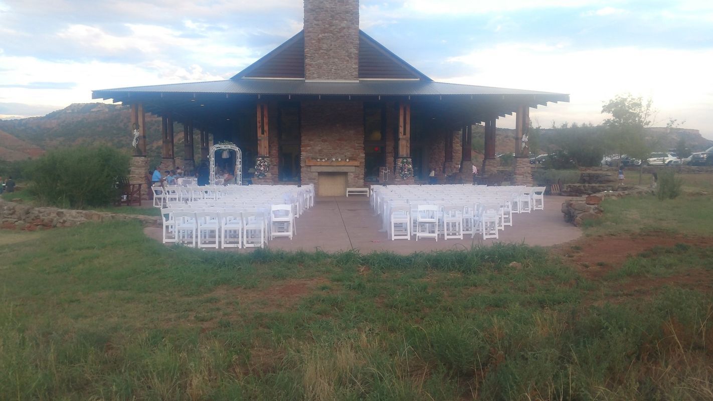 A row of white chairs are lined up in front of a large building