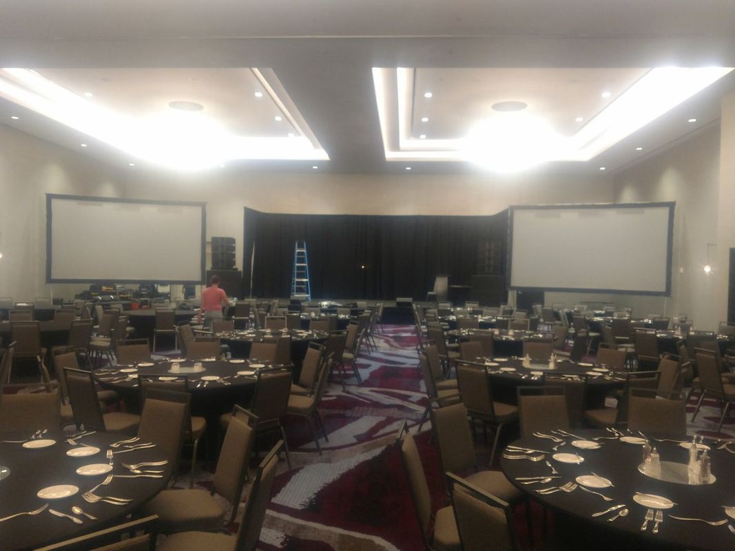 A large room with tables and chairs and projector screens