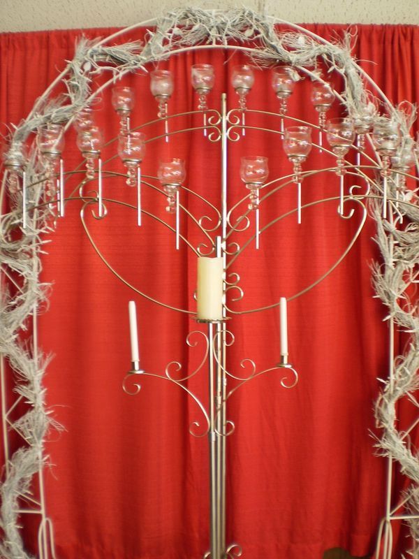 A candelabra with candles and wine glasses in front of a red curtain