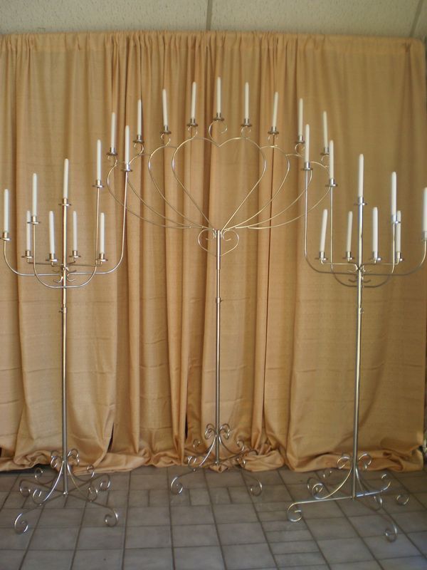 A group of candle holders are sitting in front of a tan curtain