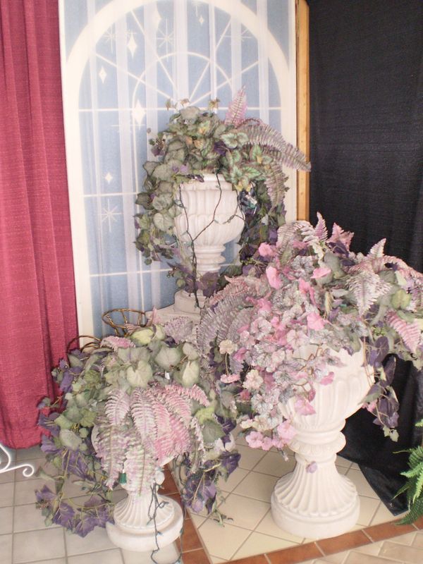 Two vases filled with purple flowers are in front of a window