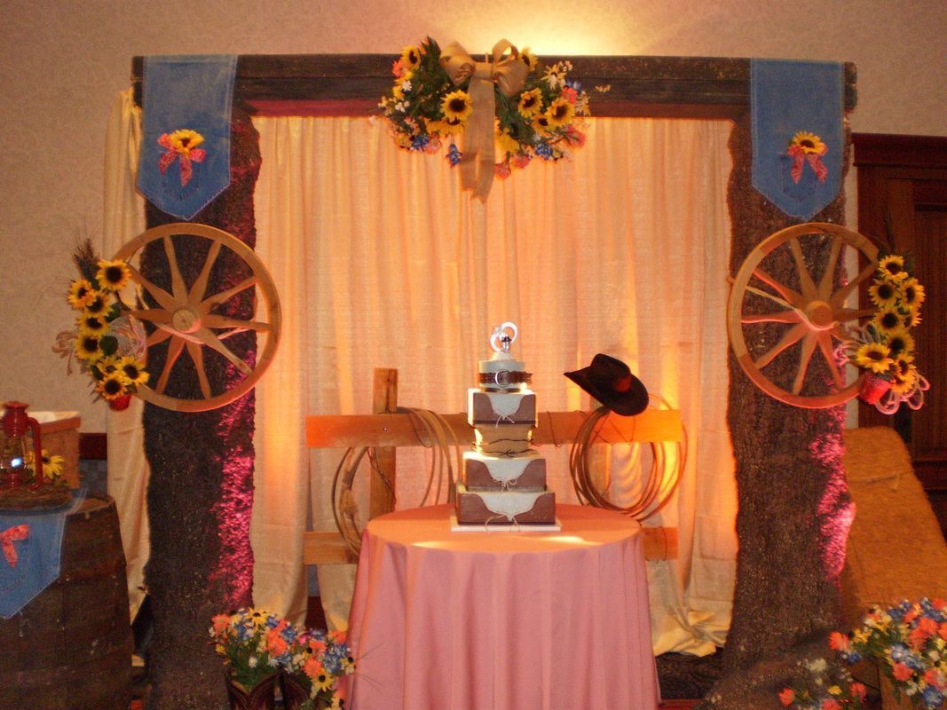 A cake on a table in front of a wagon wheel