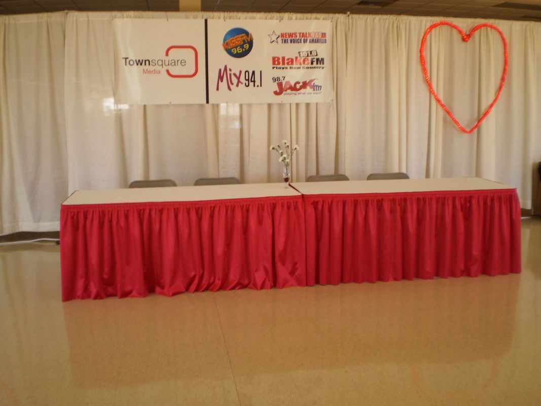 A long table with a red skirt and a heart on the wall behind it