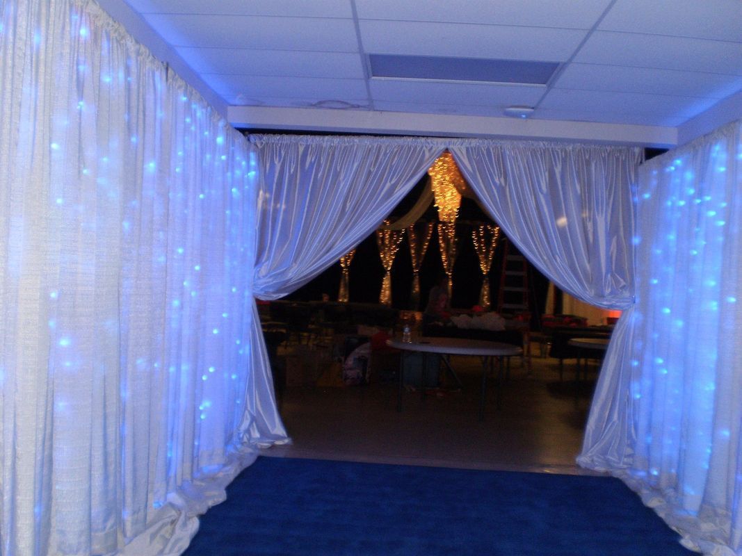A hallway with white curtains and blue lights on the walls