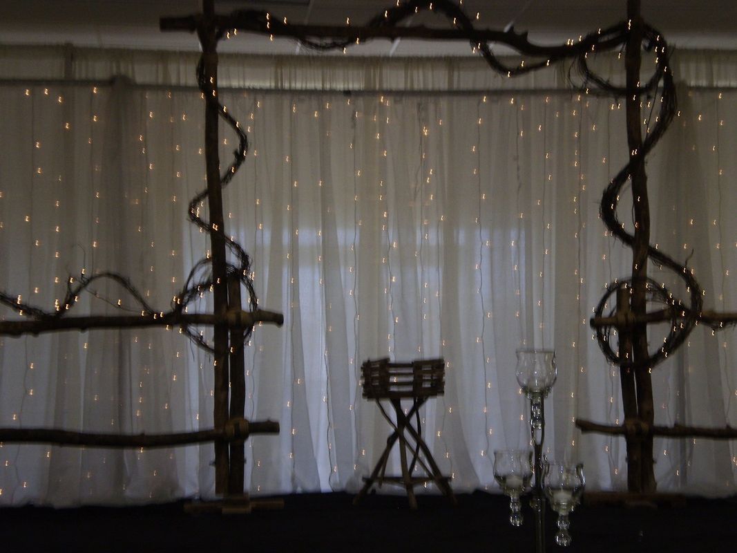A room with a table and a chair in front of a white curtain