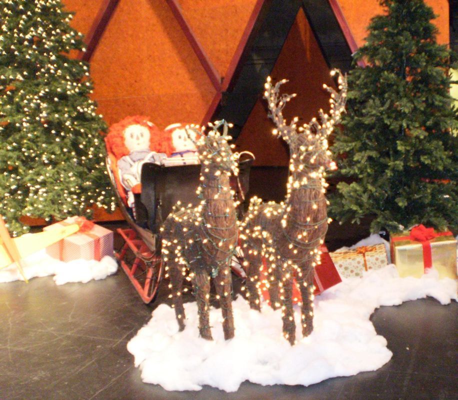 Two reindeer pulling a sleigh with two dolls in it