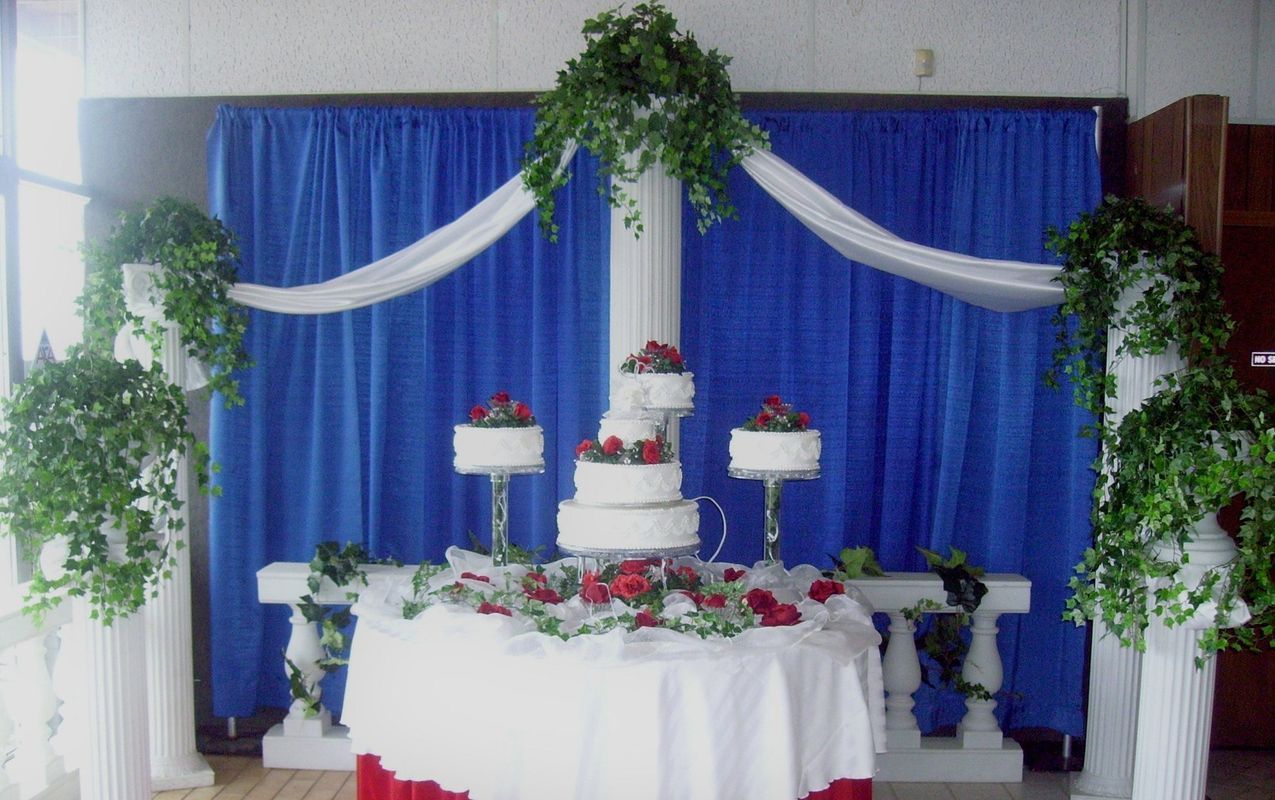 A wedding cake on a table in front of a blue curtain