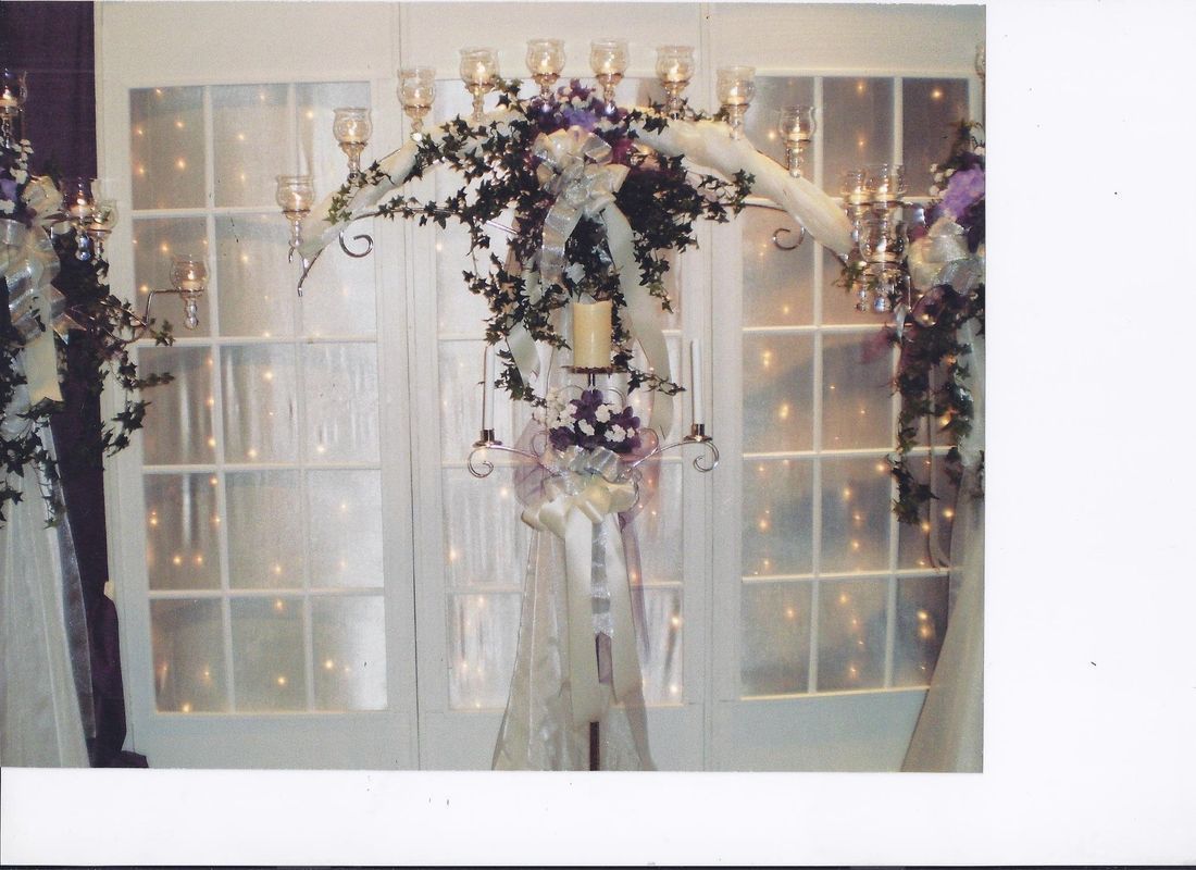 A picture of a wedding arch with candles and flowers