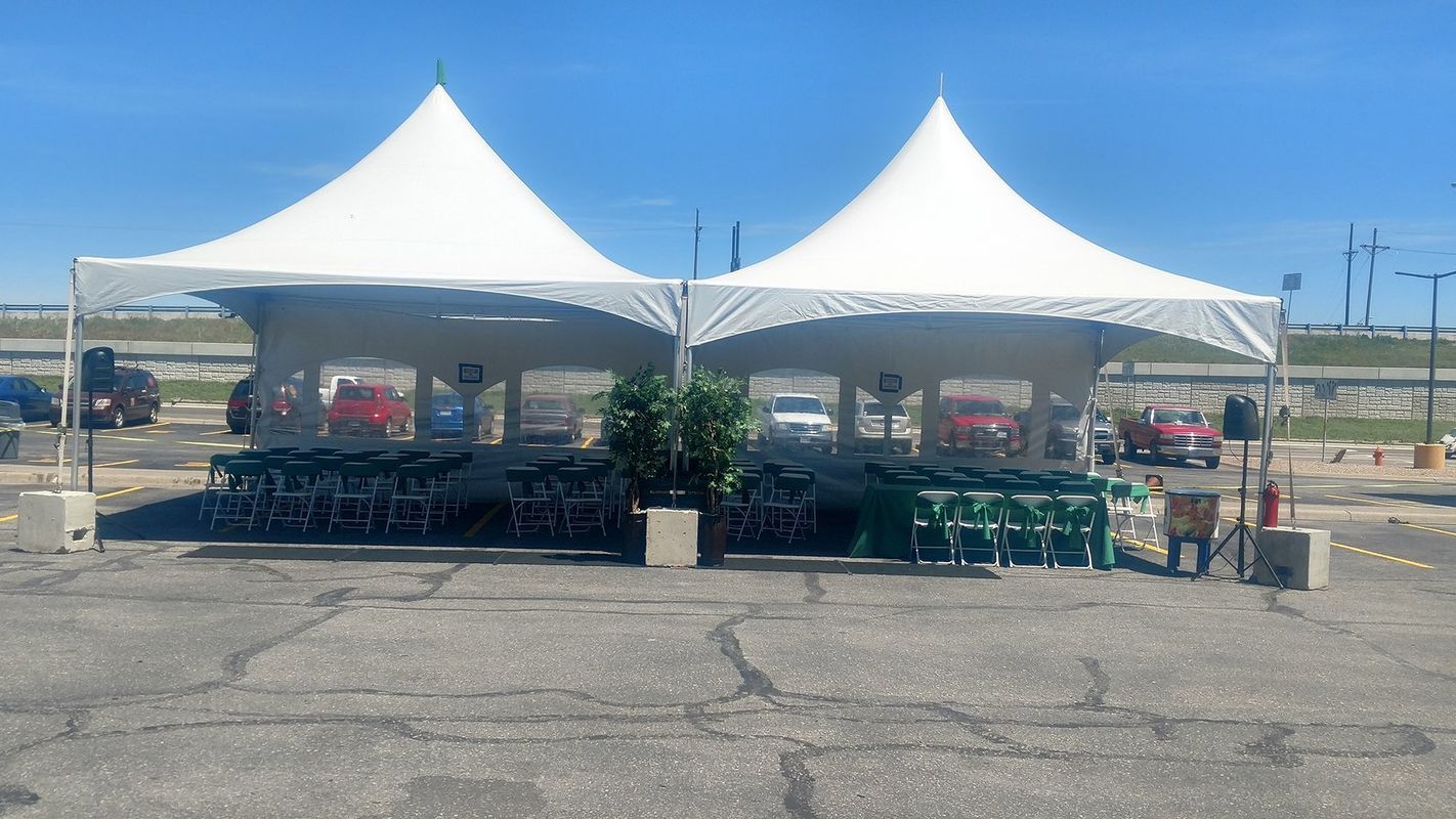 Two white tents are sitting in a parking lot