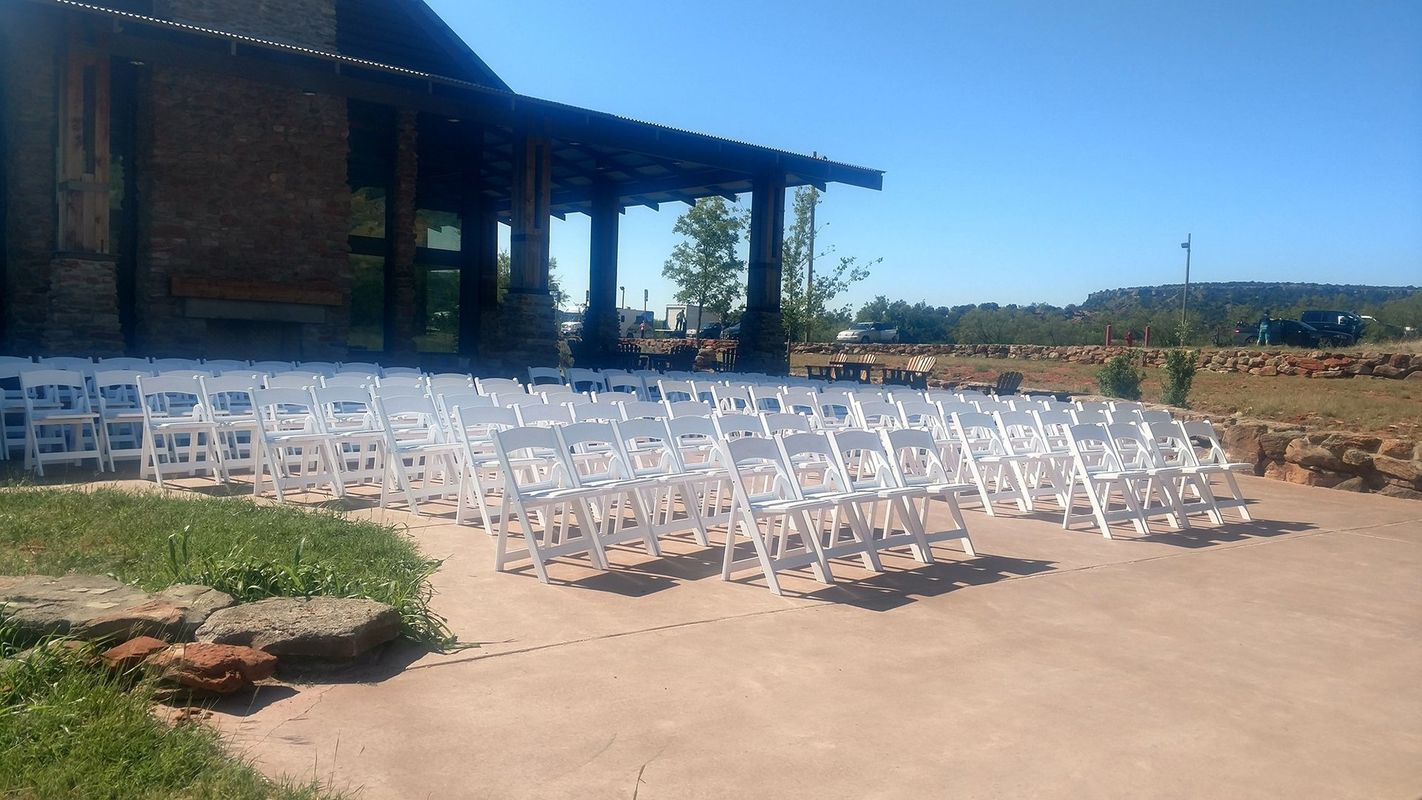 A row of white chairs are lined up in front of a building
