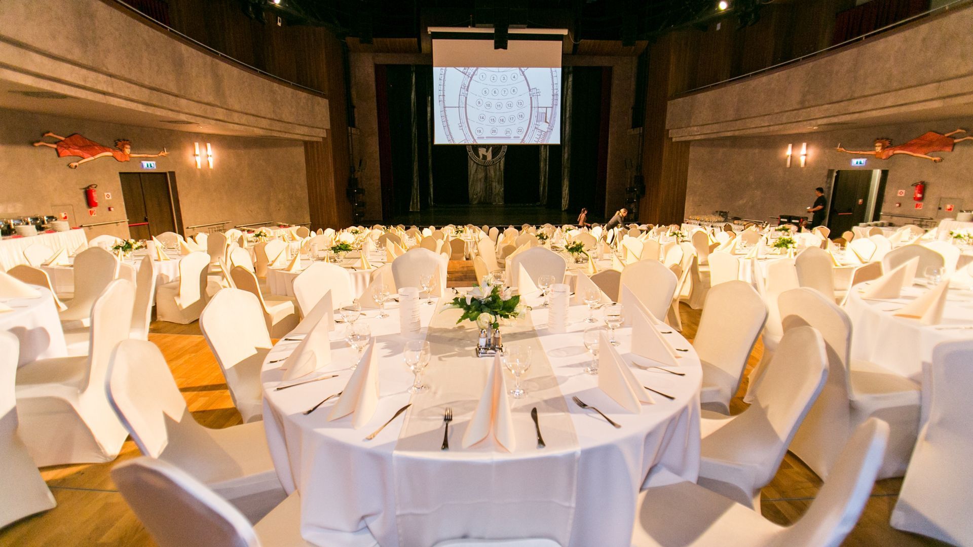 A large room with tables and chairs set up for a wedding reception