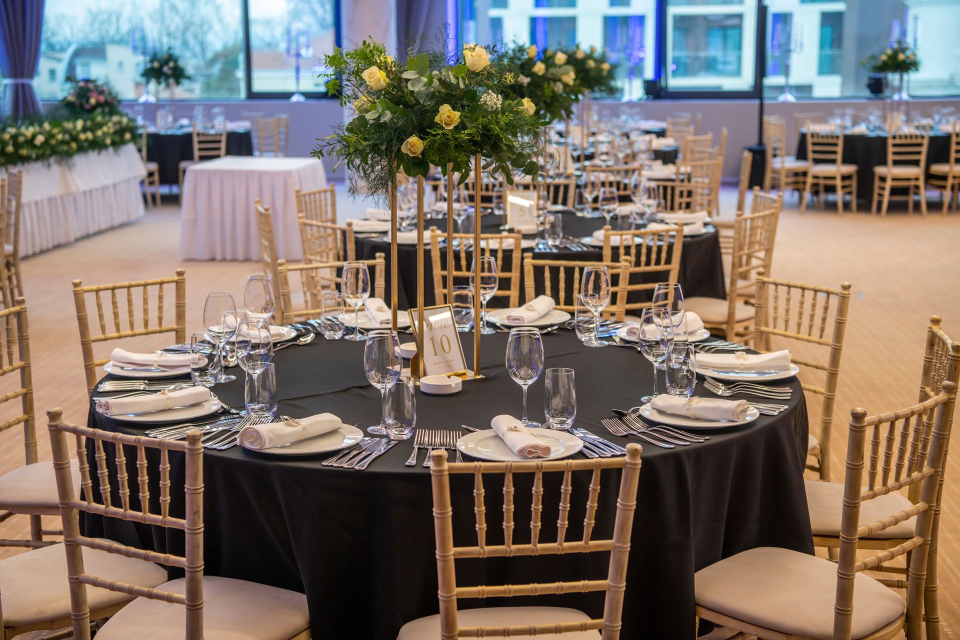 A large room with tables and chairs set up for a wedding reception