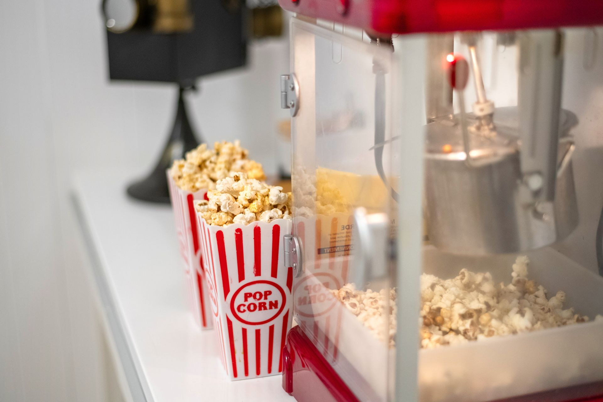 Two buckets of popcorn are sitting on a table next to a popcorn machine