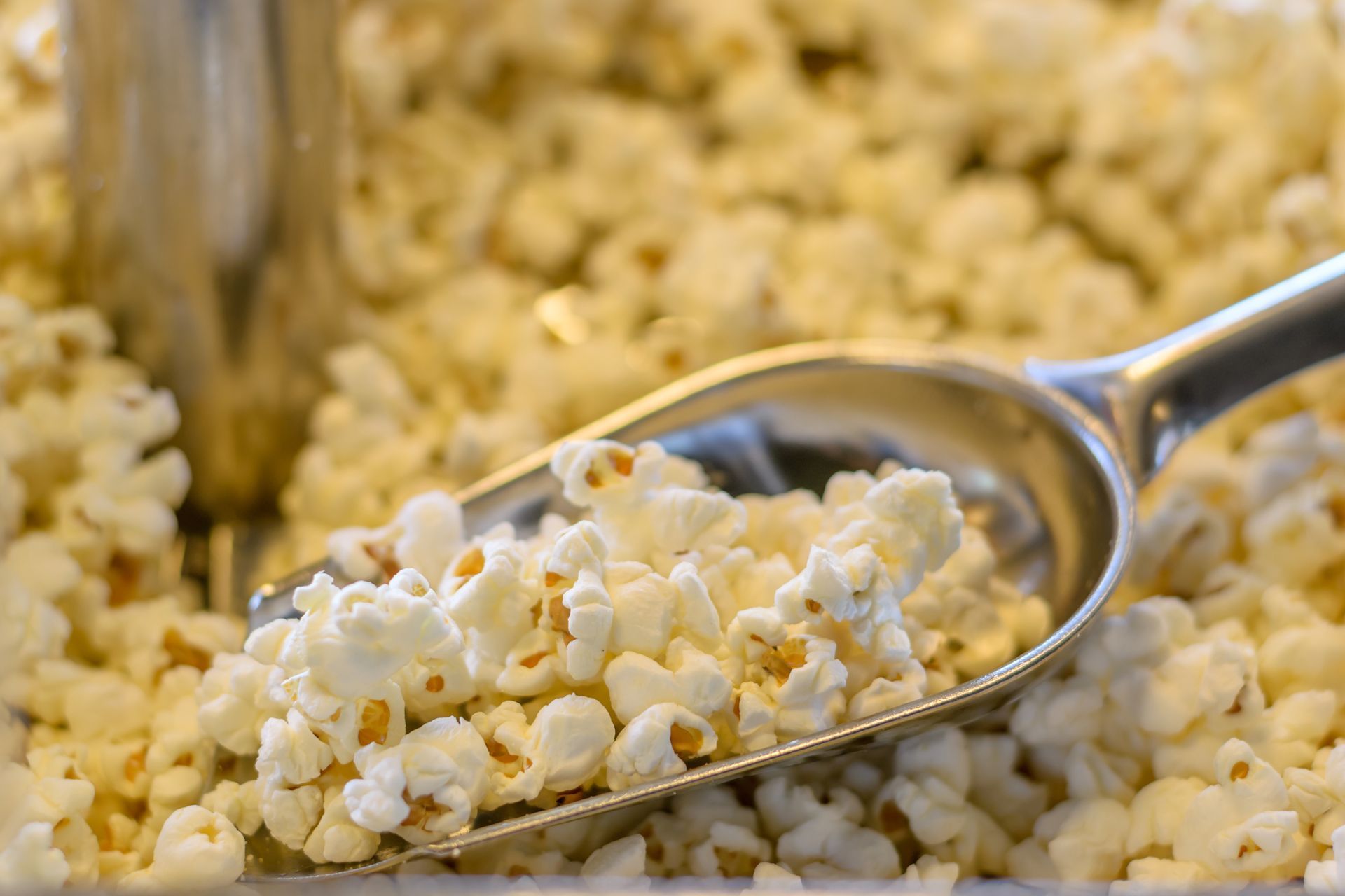 A scoop of popcorn is being poured into a bowl of popcorn