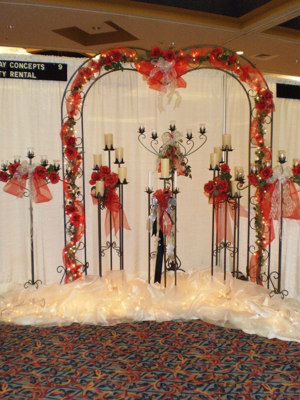 A wedding arch with candles and flowers in front of a sign that says concepts