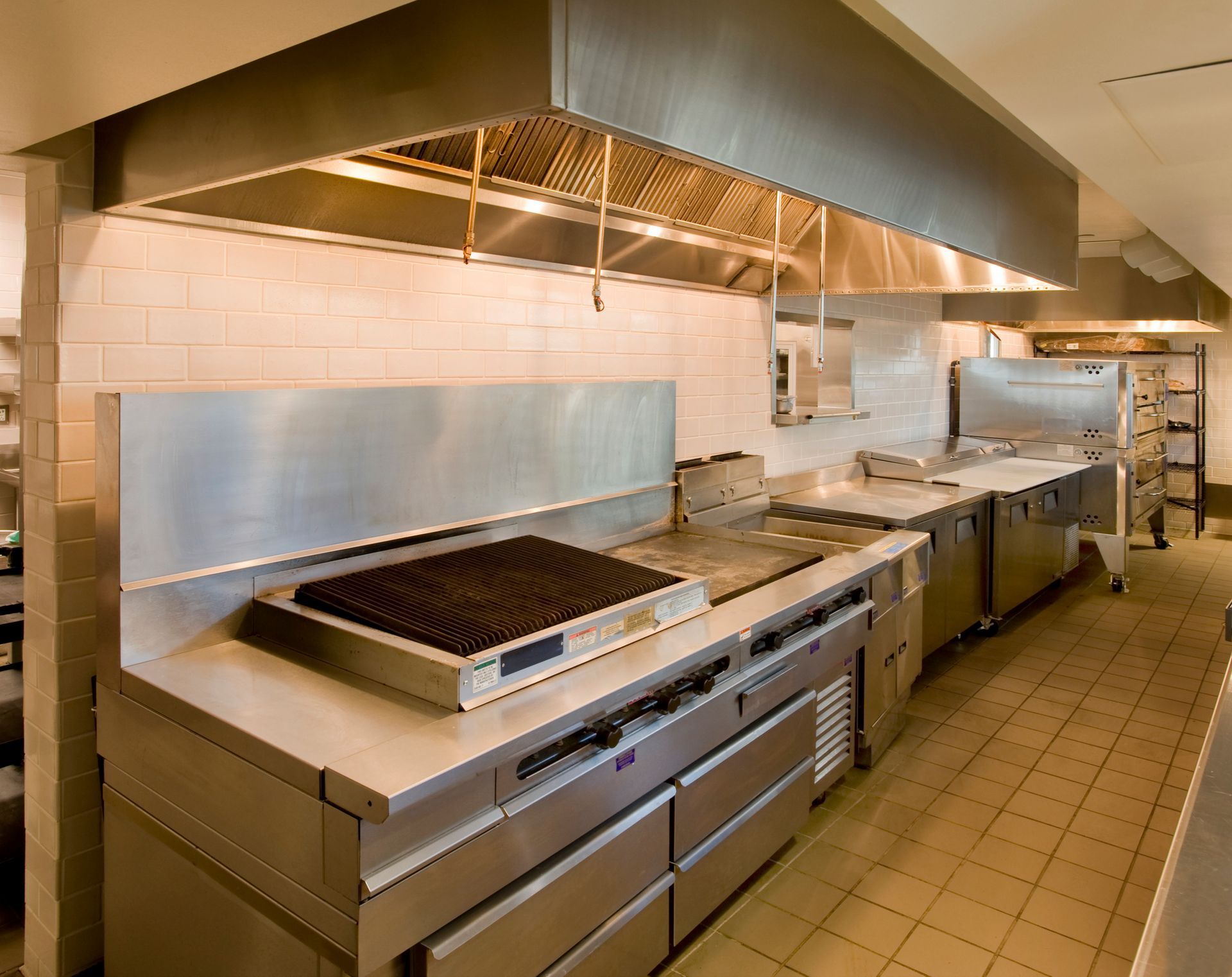Commercial kitchen hood installation in a modern kitchen with stainless steel appliances.