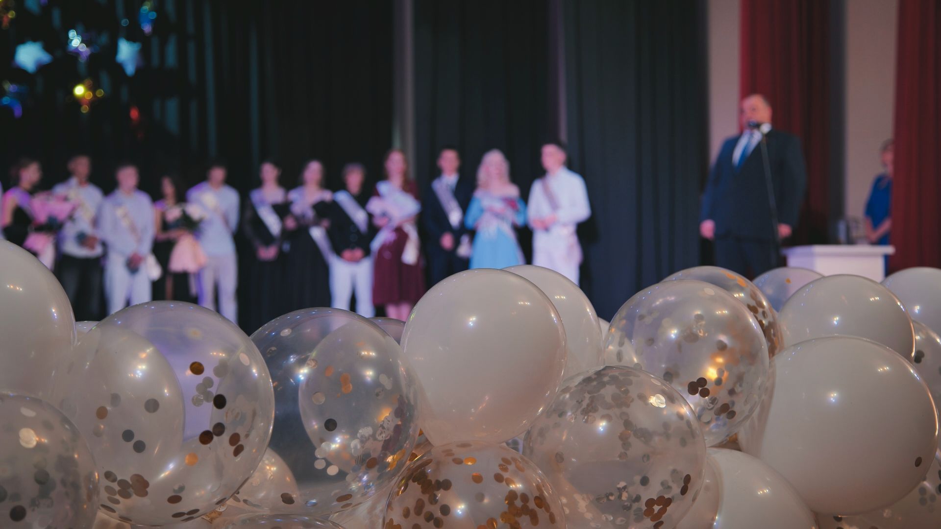 Party decorations with balloons, a cake, and a pink box.