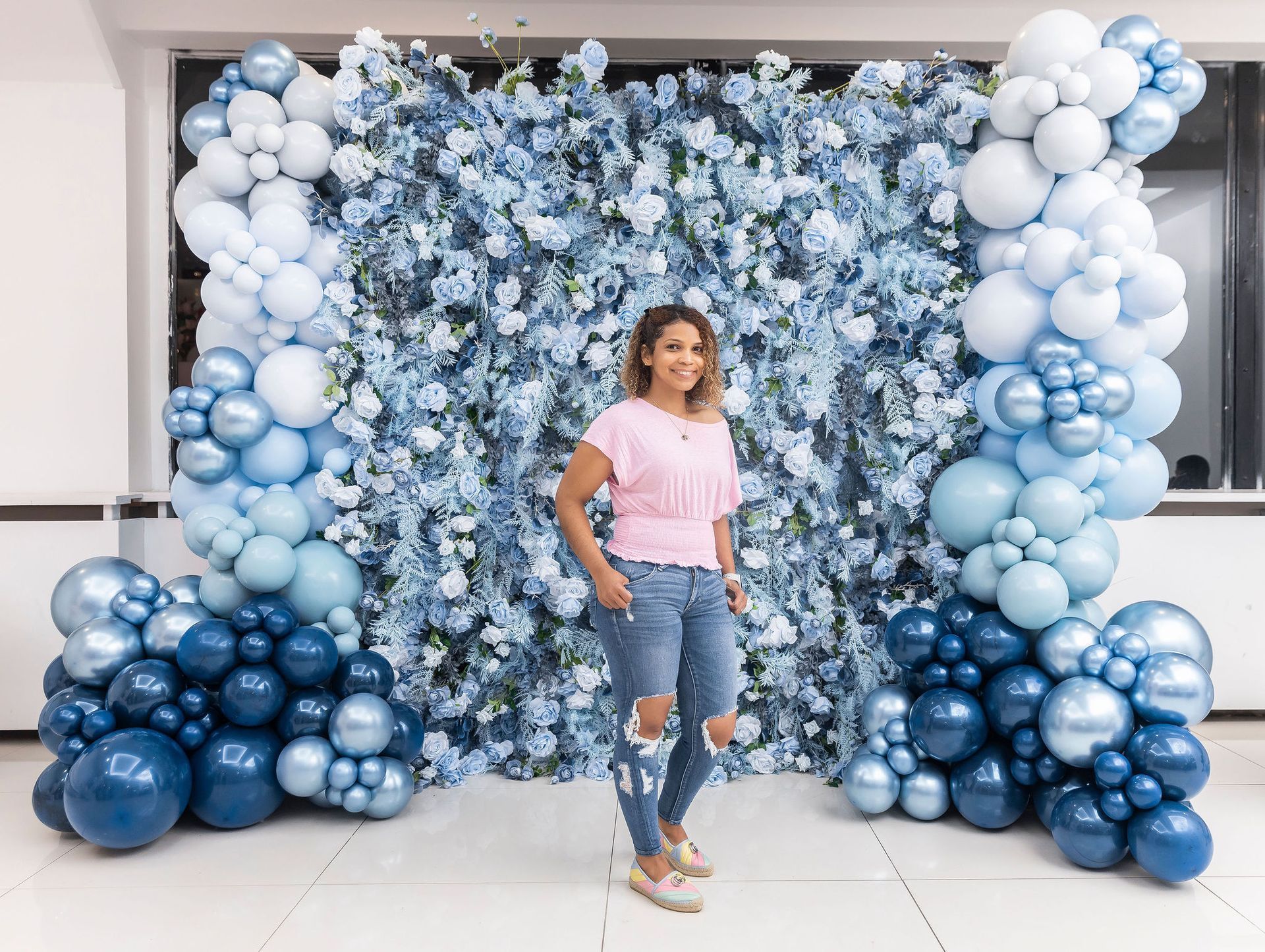 Woman standing in front of a blue floral and balloon backdrop.
