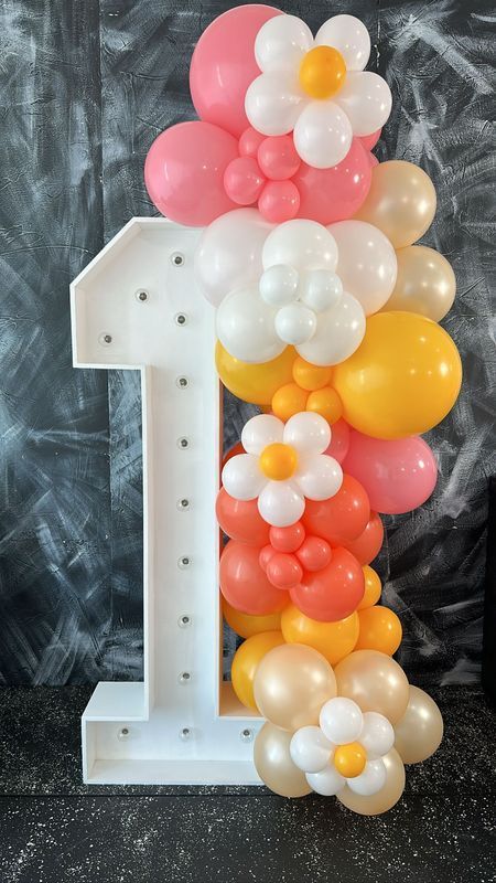 White number 1 with daisy balloon garland in pink, orange, yellow, and white.