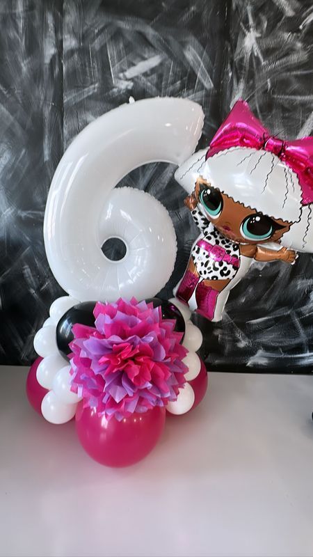 Balloon centerpiece for a 6th birthday. Features a white number 6, LOL doll balloon, and pink and white balloons.
