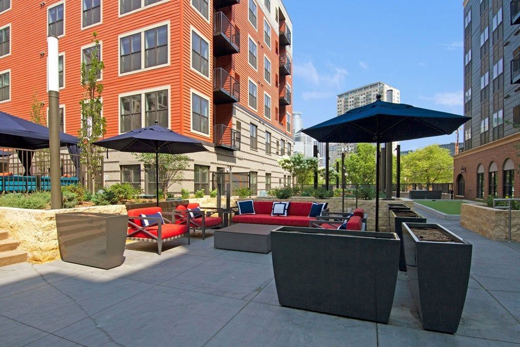 A patio with a lot of furniture and umbrellas in front of a building.