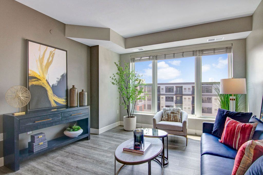 A living room with a couch , chair , coffee table and large windows.