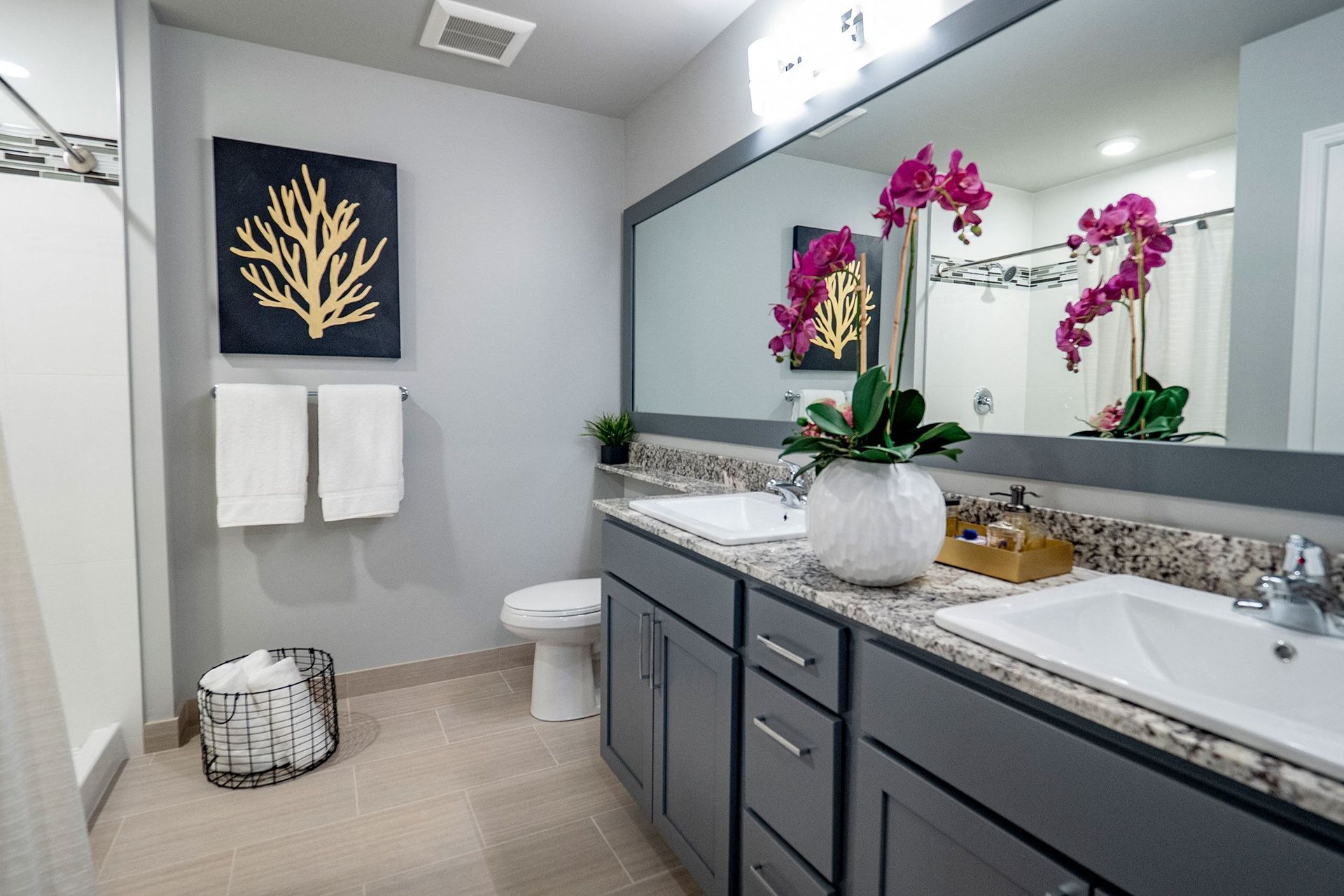 A bathroom with two sinks , a toilet , and a large mirror.