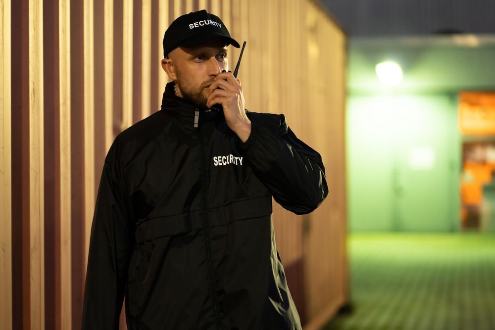 A security guard is talking on a walkie talkie.