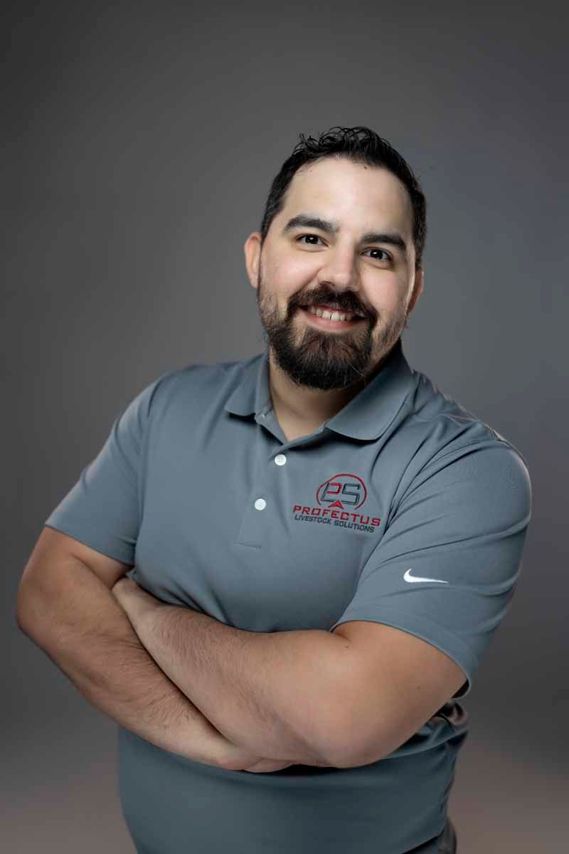 Man with a beard in a gray polo shirt, arms crossed, smiling. Gray background.