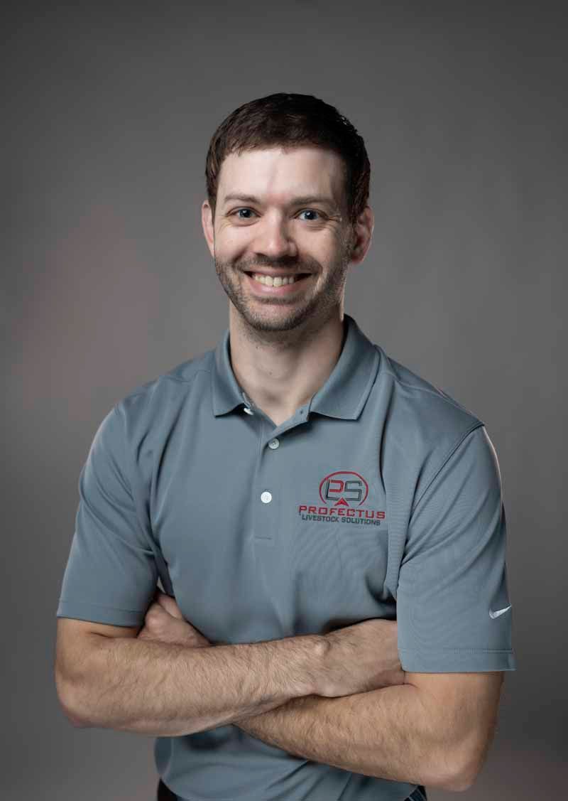 Smiling man in a gray polo shirt with crossed arms, standing in front of a gray background.