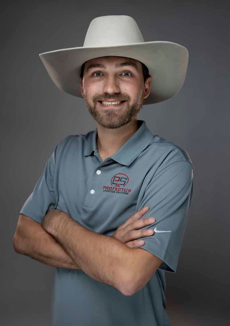 Man wearing a cowboy hat and grey polo shirt with arms crossed, smiling.