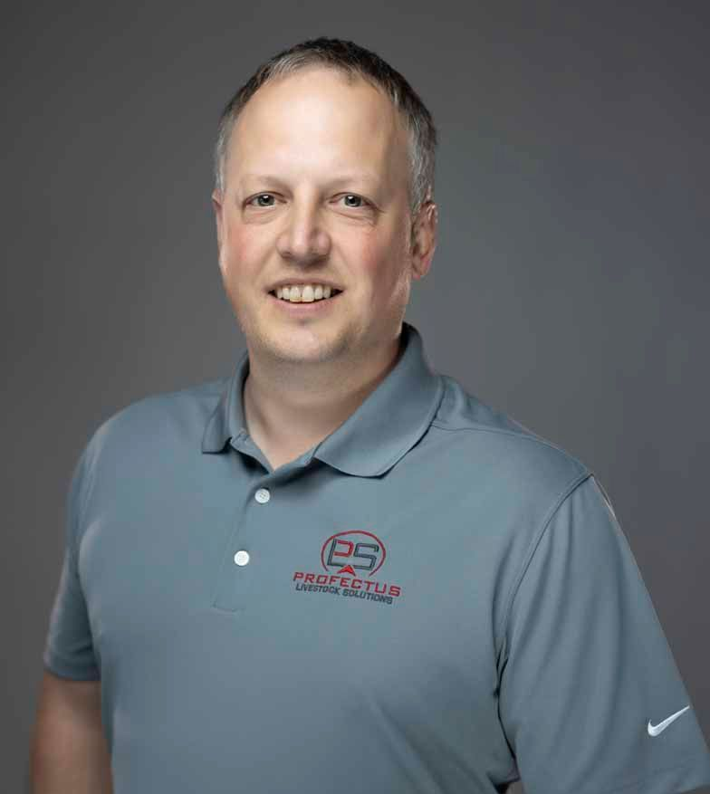 Man in a gray polo shirt smiles at the camera. The shirt has a logo and a small Nike emblem. He is against a gray backdrop.