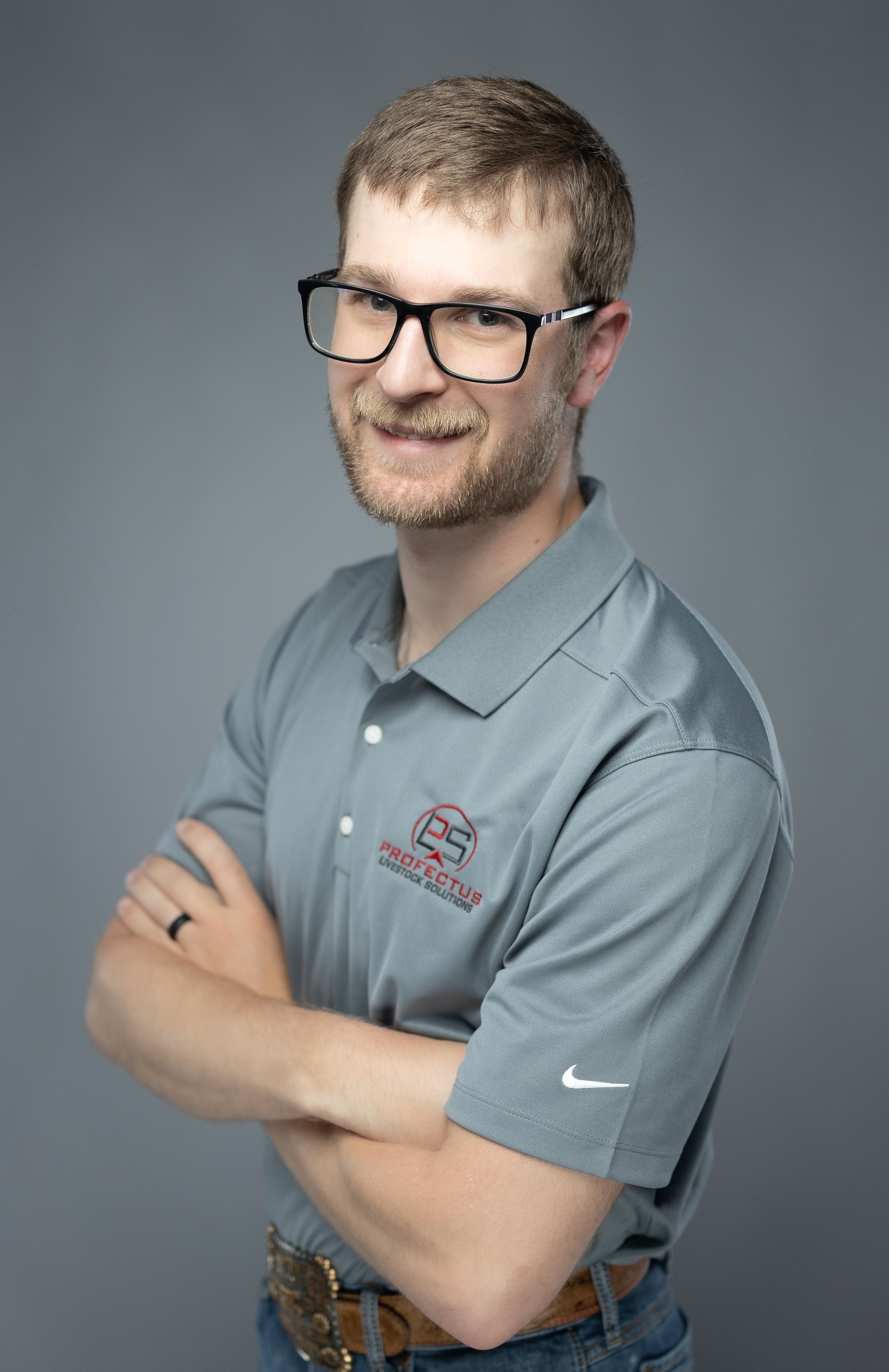 Man wearing a cowboy hat and grey polo shirt with arms crossed, smiling.