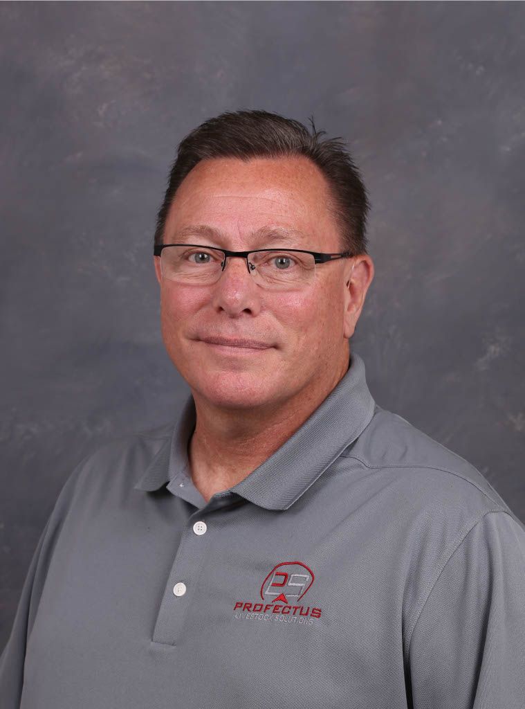 Man with glasses, arms crossed, wearing a gray polo shirt over a black shirt, smiling against a gray background.