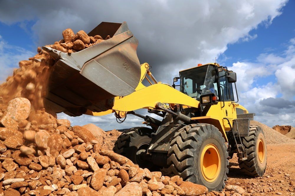 Front End Loader Dumping Stones & Sand In Quarry — Construction Supplies in Rockhampton, QLD