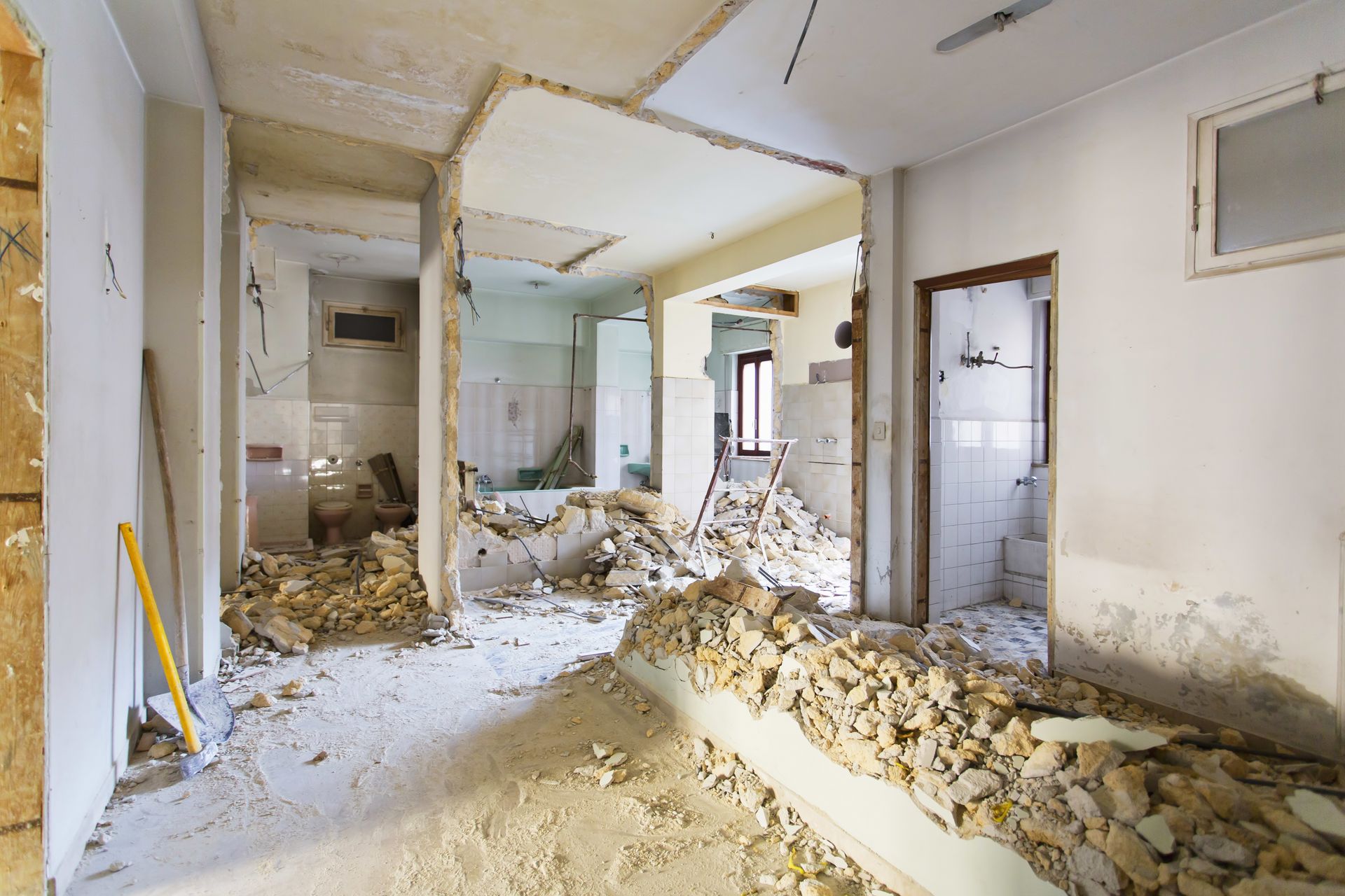 Damaged interior with rubble piles, exposed walls, and debris-covered floor in an abandoned room