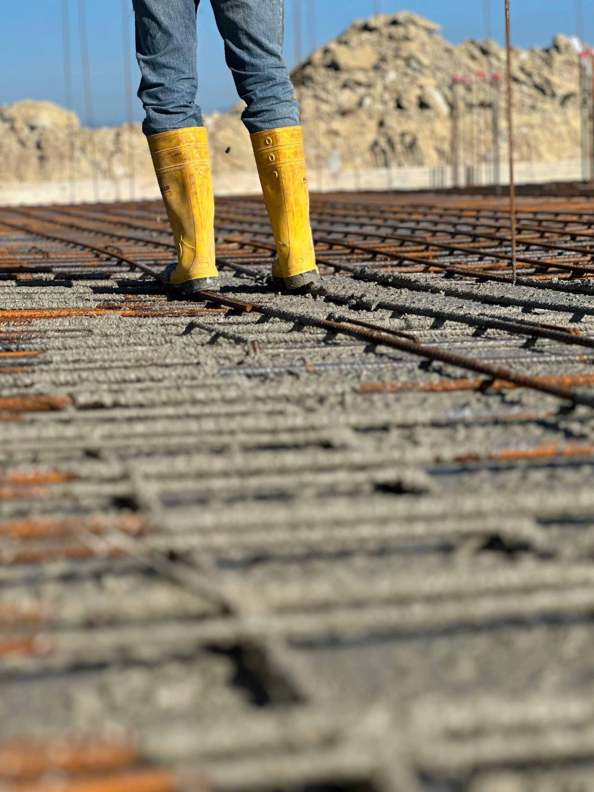 Worker in yellow boots standing on rebar at a construction site
