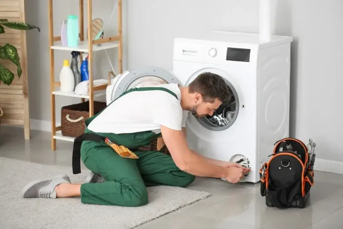 Professional technician repairing a white washing machine.