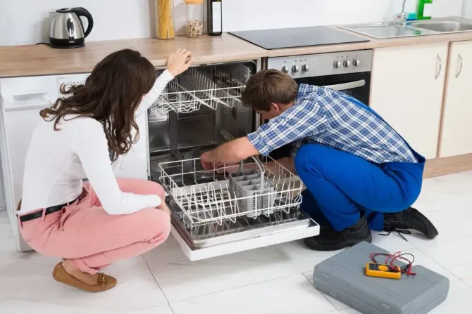 Professional technician repairing a kitchen dishwasher.